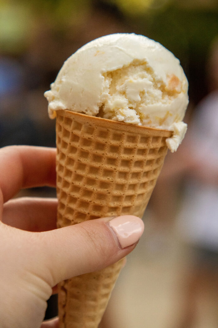 Peach ice cream on a sugar honey cone in a person's hand